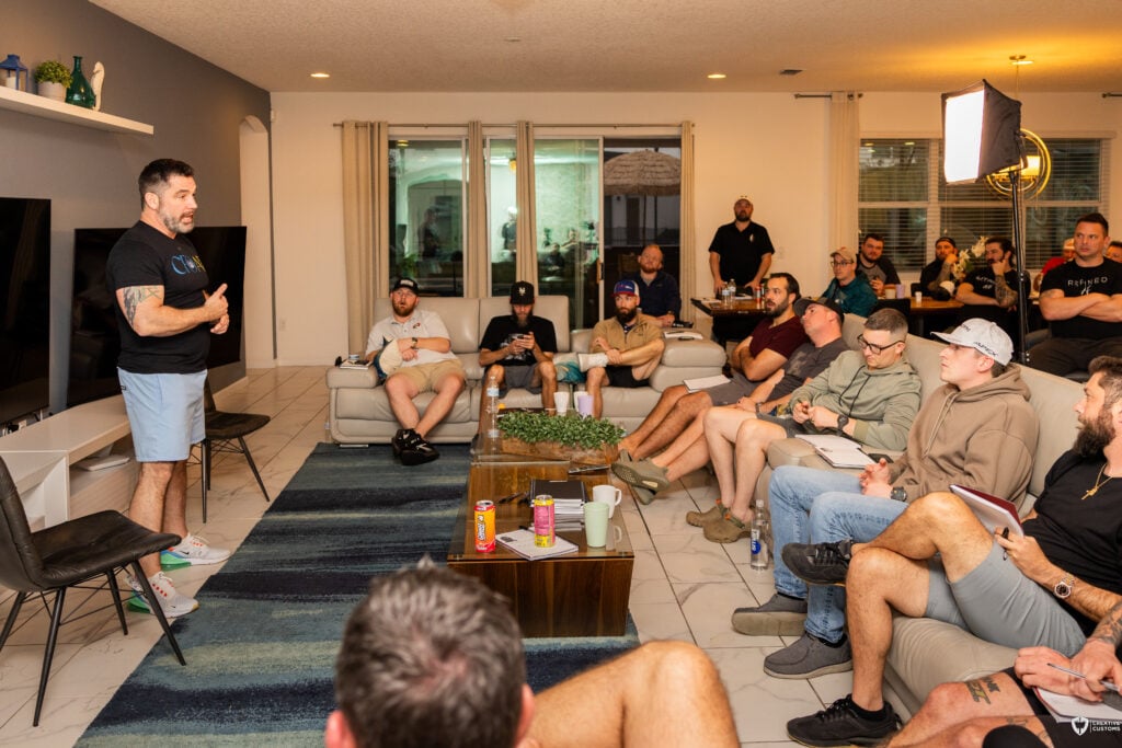 A group of men at an Uncaged Men’s Accountability Group session, attentively listening to a speaker discussing financial protection, business partnerships, and risk management.