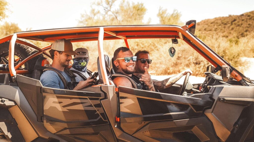 Four men in an off-road RZR, smiling and enjoying a high-adventure experience during an Uncaged Men’s Accountability Group retreat.