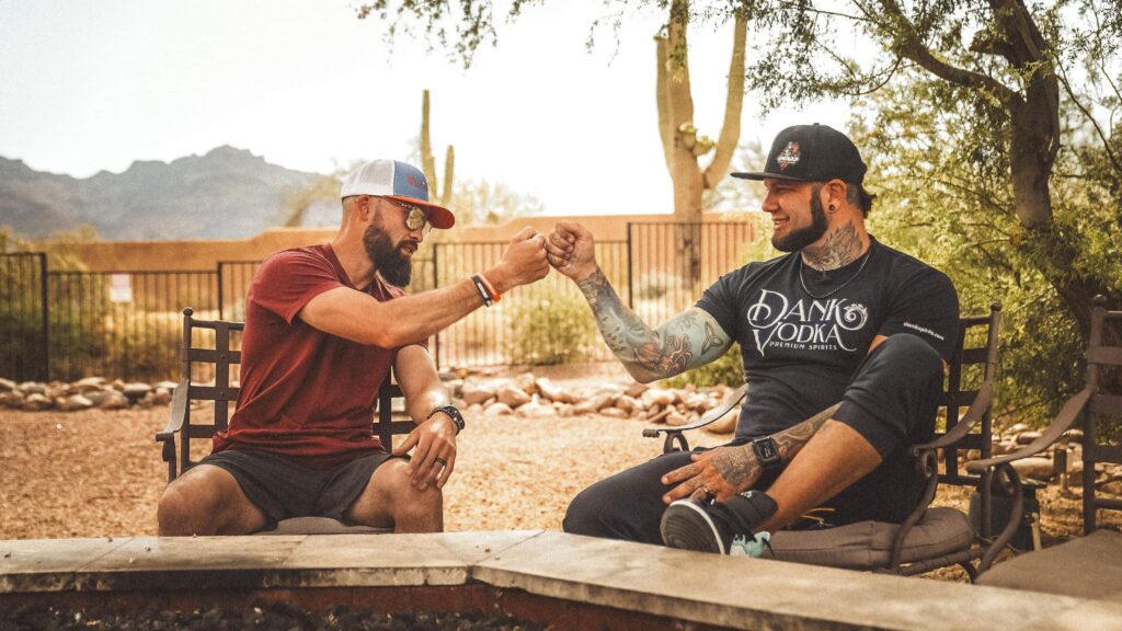Dillin Brissette and Zack Williams sharing a fist bump during an Uncaged Men’s Accountability Group conversation about fatherhood and personal growth in an outdoor setting.