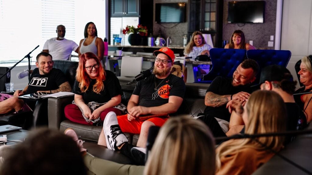A group of men and women engaging in a powerful, high-energy discussion at an Uncaged retreat, focusing on eliminating excuses and achieving success in personal and professional growth.