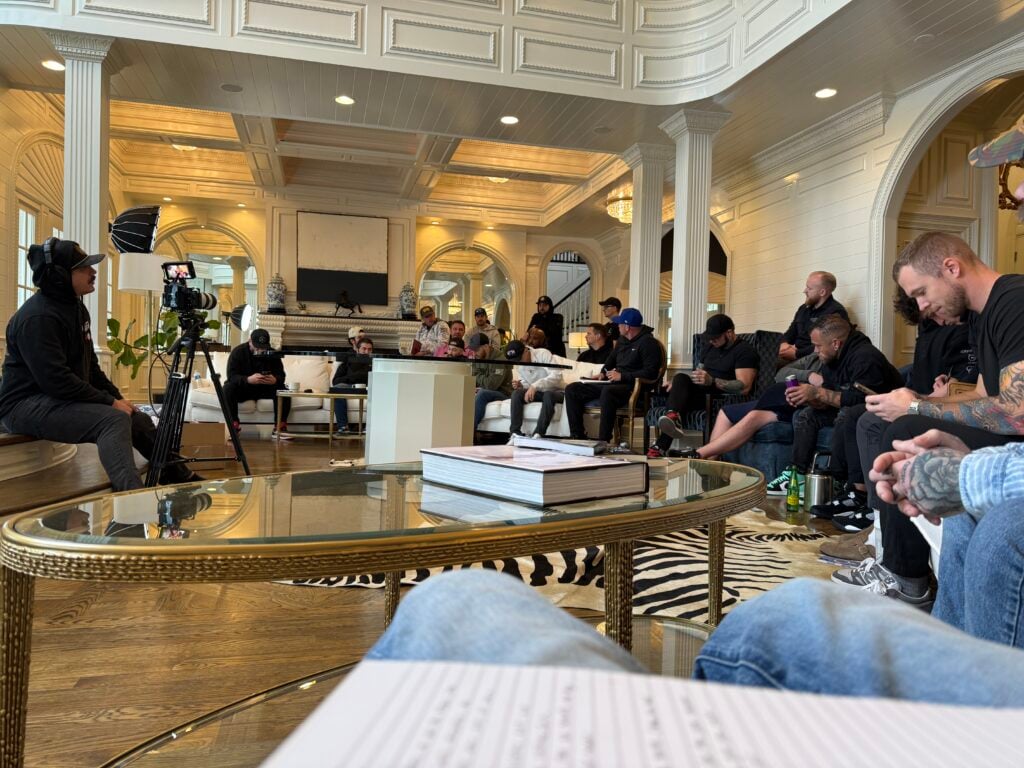A group of men at an Uncaged Men’s Accountability Group event, engaged in deep discussion and personal development in a high-performance setting.