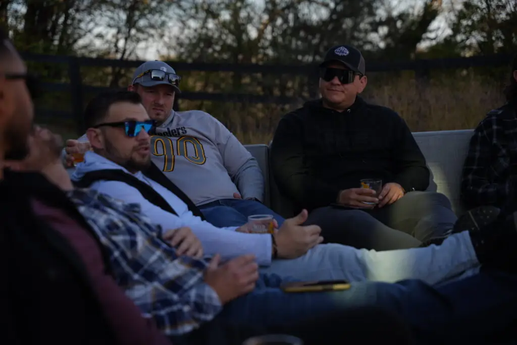 Group of men at an Uncaged Accountability Event, engaged in deep discussion about personal and professional growth while enjoying a relaxed outdoor setting.
