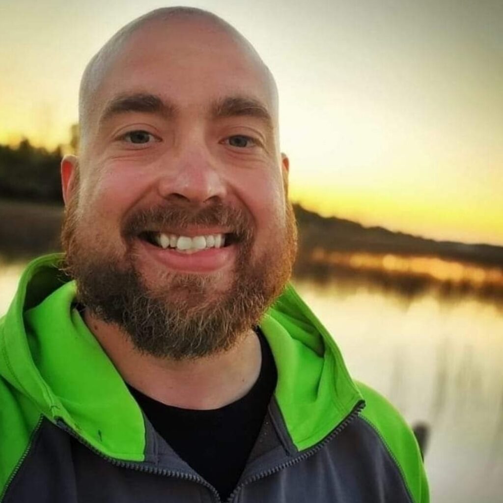 Brent Schlangen smiling outdoors at sunset, representing his journey of finding success through vulnerability, communication, and small wins with the Uncaged Men’s Only Accountability Group.